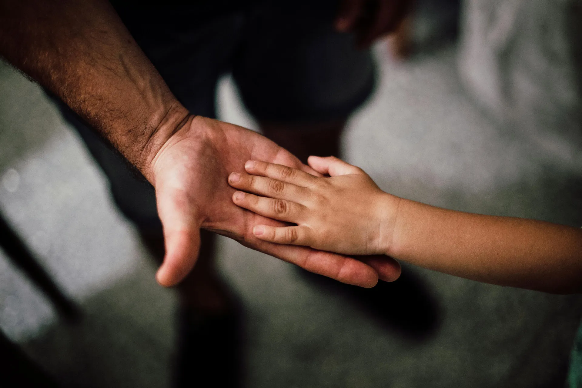 Child gently holding an adult's hand symbolizing care and guidance.