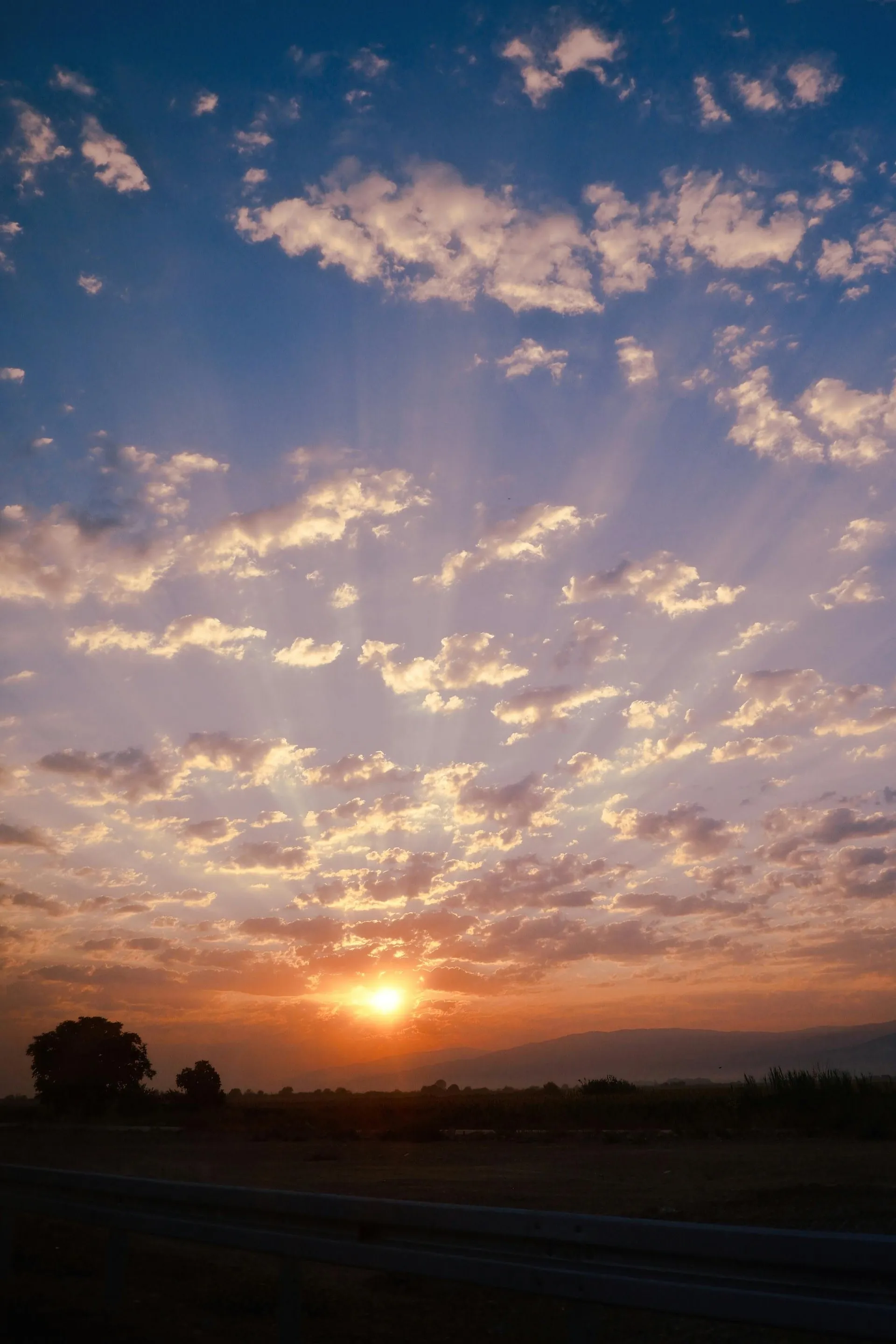 Sunrise breaking through scattered clouds with rays of light illuminating the morning sky.