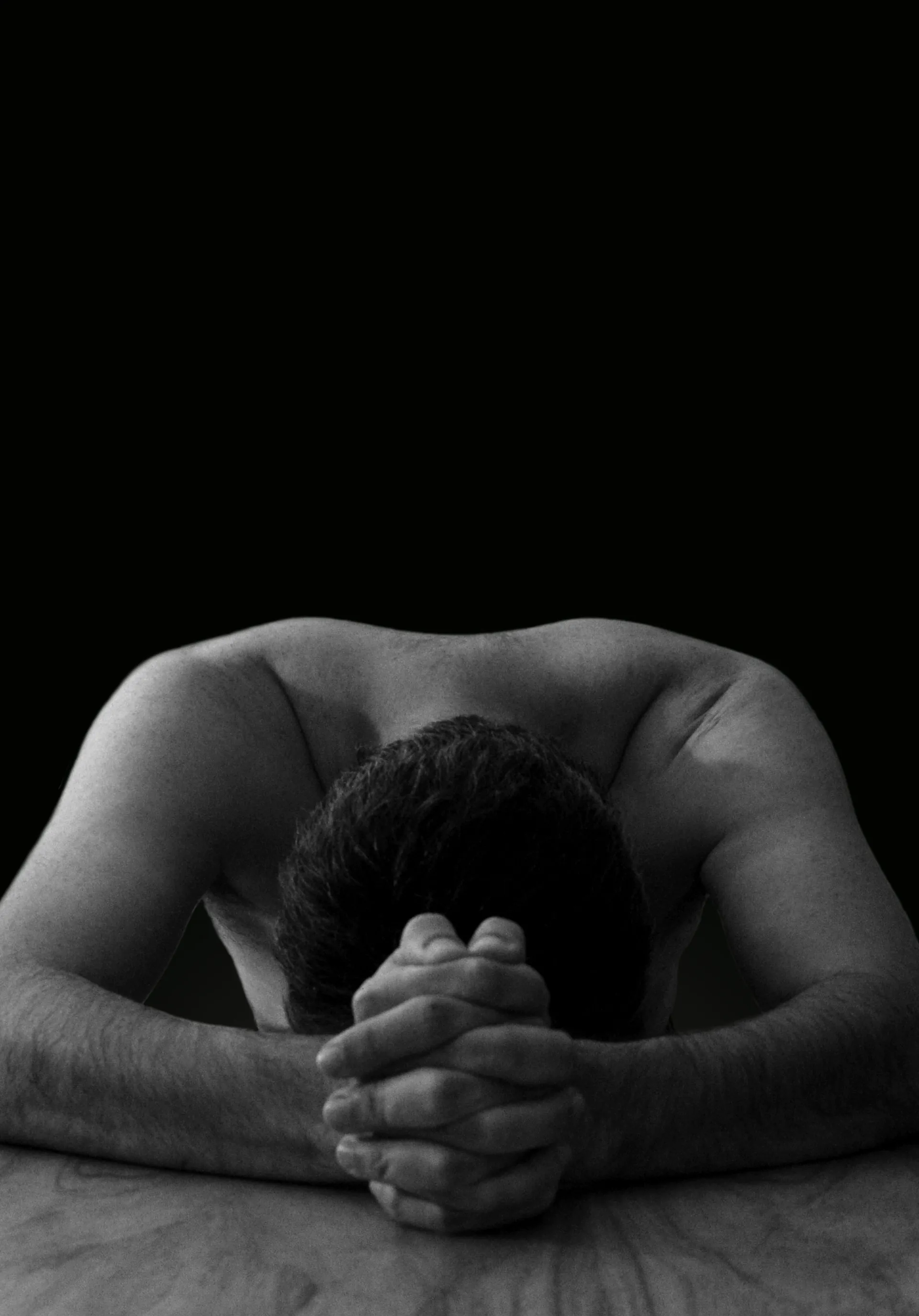 A man with his head bowed and hands clasped in prayer, expressing humility and seeking God's help.
