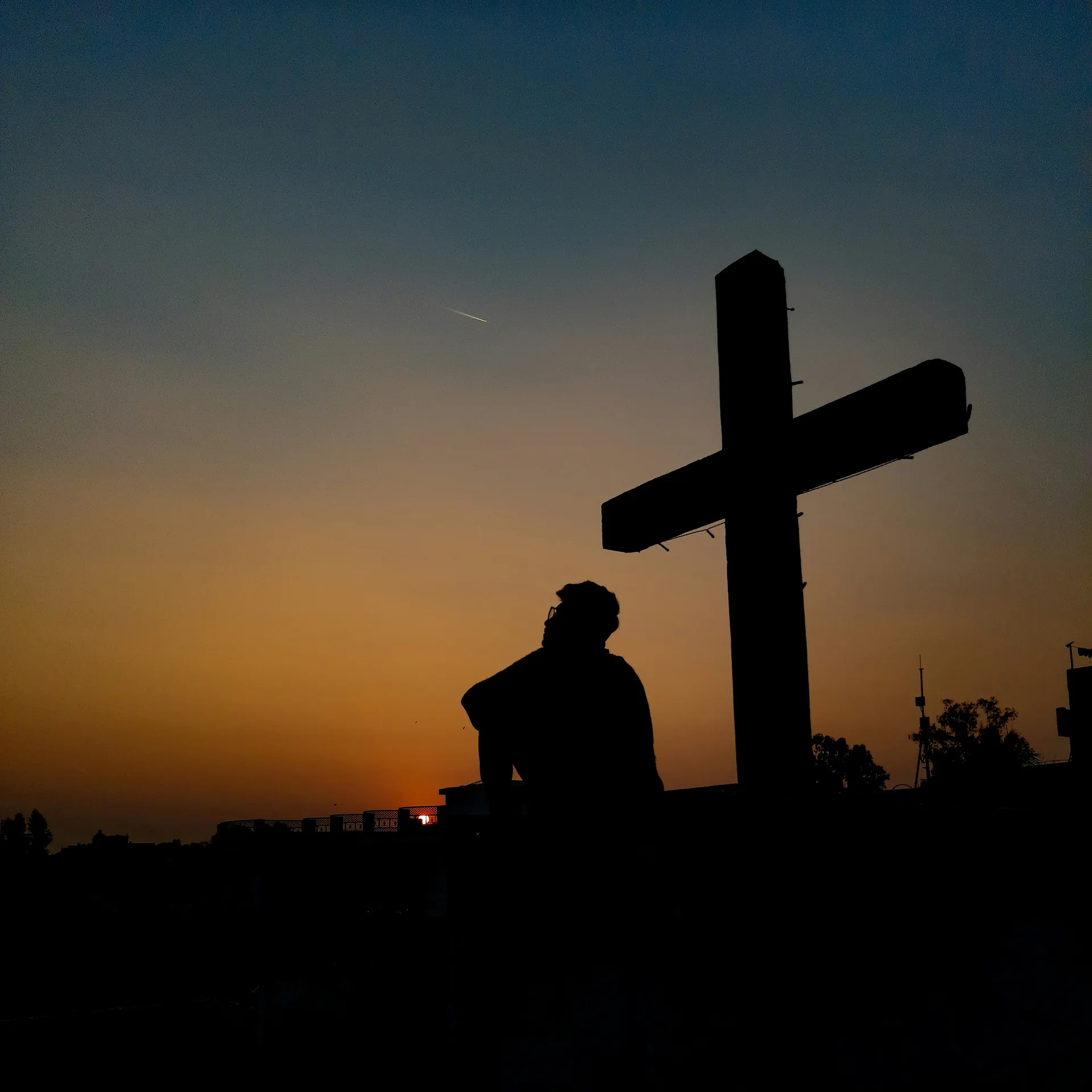 Una cruz recortada contra un cielo brillante al atardecer.